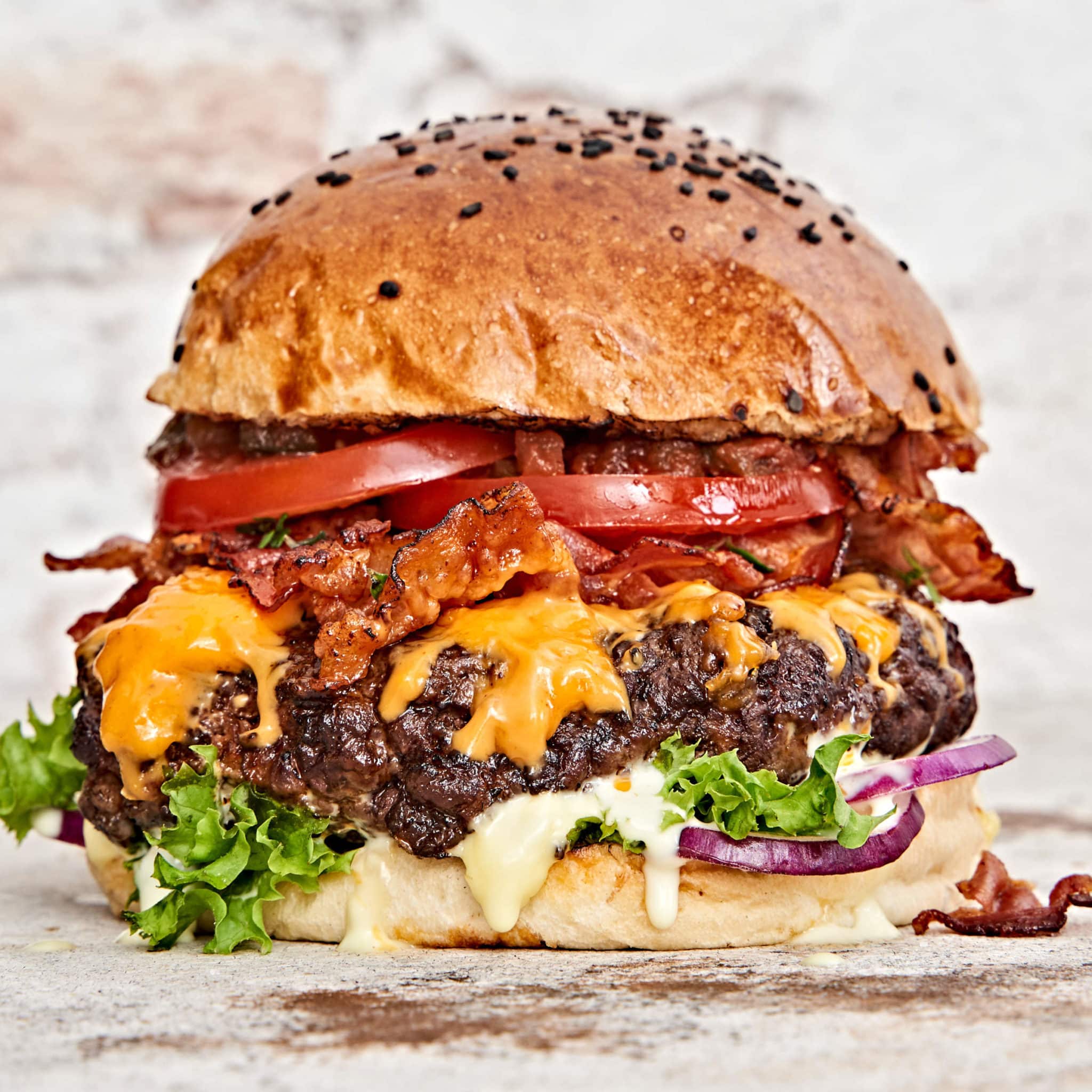 Beefbursters Burger mit Speck, Tomaten, Käse und Zwiebeln