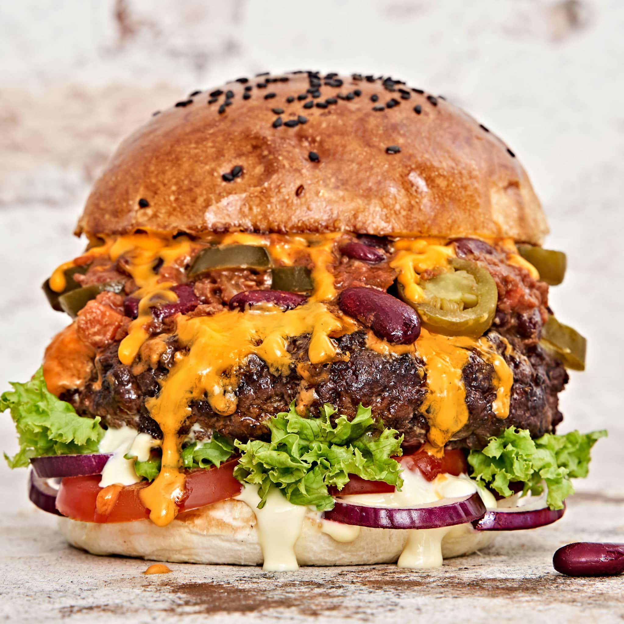 Der Chili Cheese Burger mit Jalapenos, Bohnen, Käse und Salat